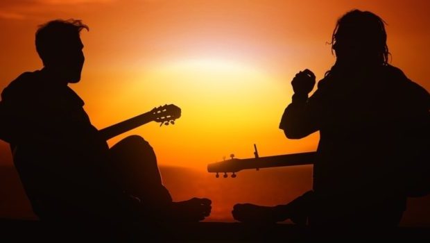 Two men in silhouette playing guitar